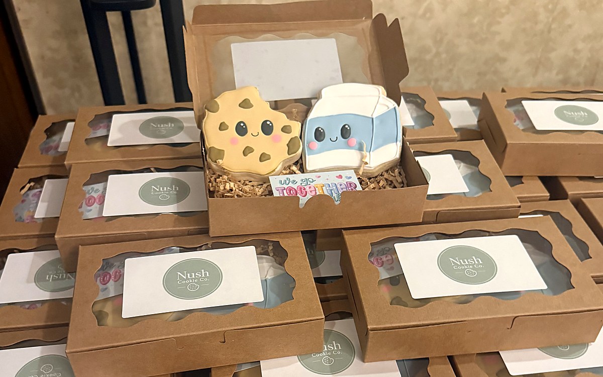 Stack of Nush Cookie Co. branded gift boxes with a featured cookie and milk decorated cookie pair